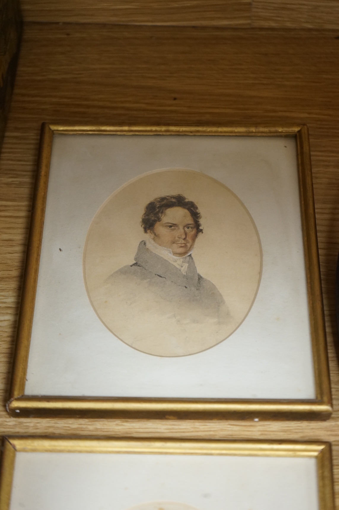 Four Regency and early Victorian portraits to include a pair of a lady and gentleman together with a carved wax bust of a lady wearing a bonnet, housed in an ebonised and gilt oval box frame, largest overall 38 x 32cm
